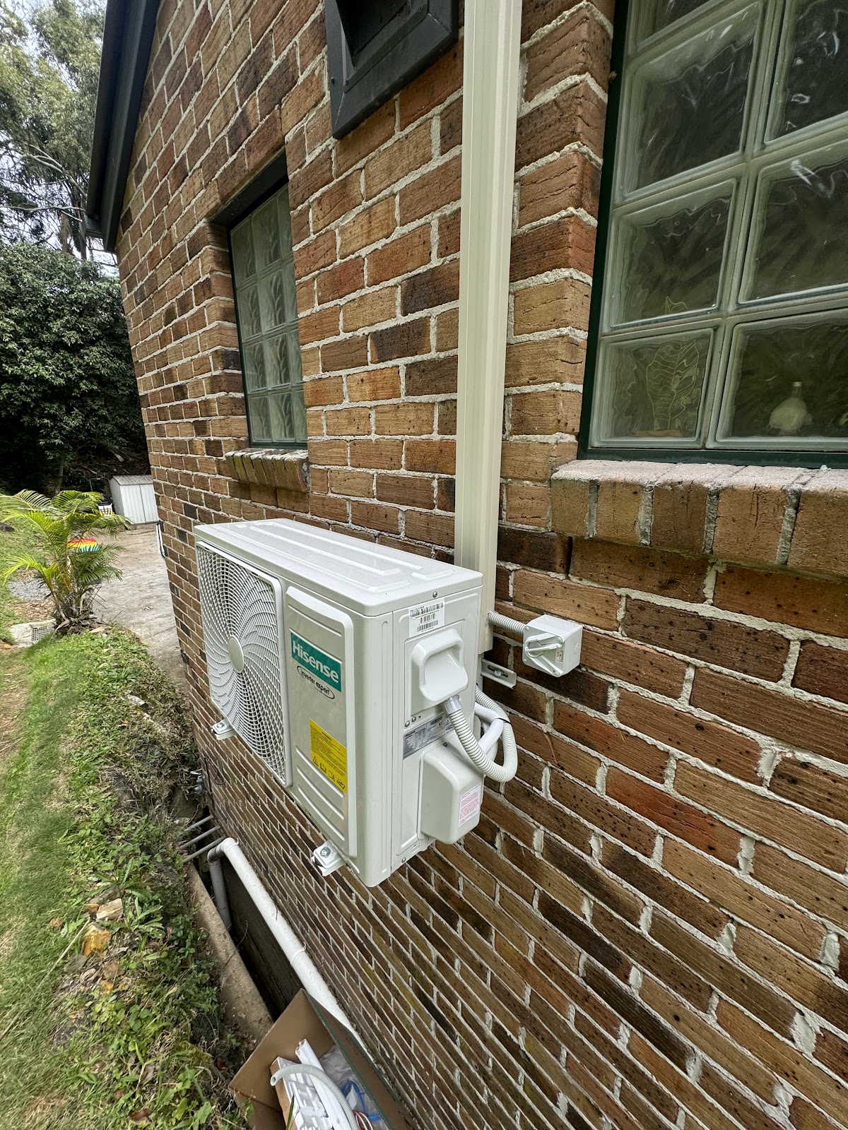 Hisense split system outdoor unit with isolator, mounted on a brick wall